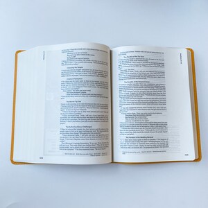 May include: Open Bible with pages showing the Gospel of Matthew, chapters 21 and 22. The text includes the Parable of the Fig Tree, the Authority of Jesus Challenged, and the Parable of the Wedding Banquet.