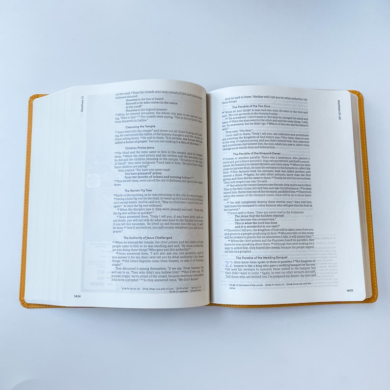 May include: Open Bible with pages showing the Gospel of Matthew, chapters 21 and 22. The text includes the Parable of the Fig Tree, the Authority of Jesus Challenged, and the Parable of the Wedding Banquet.