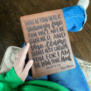 Puede incluir: Un diario de cuero marrón con la cita "WHEN YOU WALK through fire YOU WILL NOT BE BURNED, AND the flame SHALL NOT CONSUME YOU. FOR I AM THE Lord YOUR Hod"  Isaiah 43:2-3a  Eric Olsen.