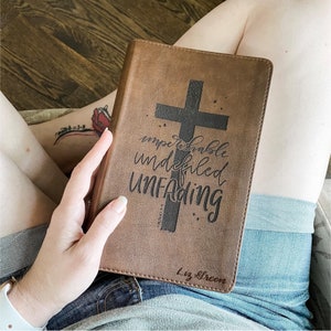 May include: A brown leather-bound book with a black cross and the words "imperishable, undefiled, unfading" printed on the cover. The book also has the name "Liz Green" printed on the cover.