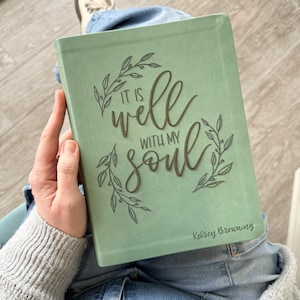 May include: A sage green book with the words "IT IS well WITH MY soul" in a decorative font. The book cover also features floral accents and the name "Kelsey Browning".