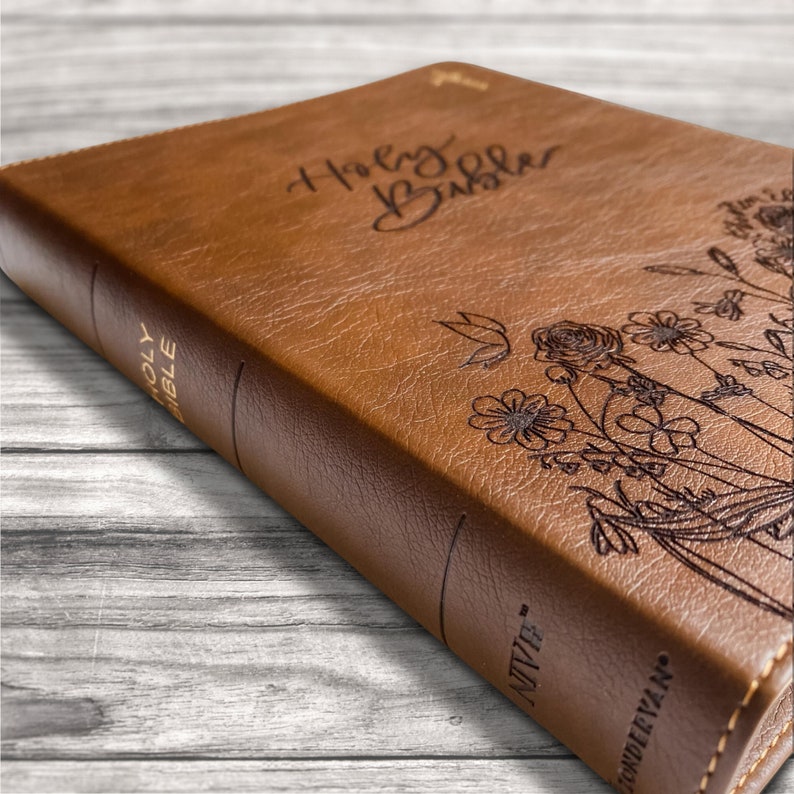 A New International Version Journaling by Zondervan Publishing in Tan. It has a design of Grass and Flowers engraved on it. It is hand lettered with calligraphy and makes a beautiful Christian gift, Gods Word, Scripture, 9780310455271