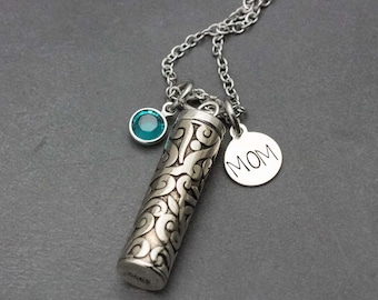 May include: Silver necklace with a small teal blue crystal charm, a silver charm with the word "MOM" engraved on it, and a silver cylinder charm with an intricate swirl design.