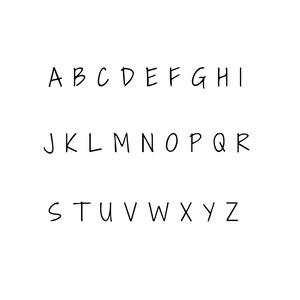 Op de afbeelding: Een handgeschreven alfabet in zwarte inkt op een witte achtergrond. De letters zijn in hoofdletters en zijn geschreven in een informele, handgeschreven stijl.