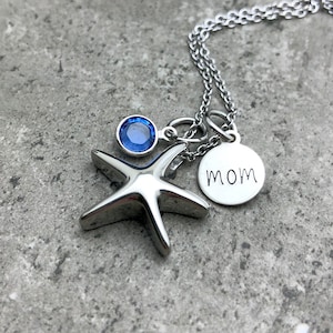 May include: A silver necklace with a starfish charm, a blue crystal charm, and a round charm that says "MOM".