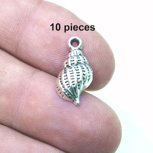 May include: Ten silver-toned seashell charms, each with a detailed design. The charms are perfect for jewelry making, scrapbooking, or other craft projects.