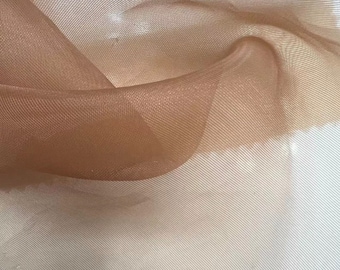 May include: A close-up of a brown sheer fabric with a fine mesh texture. The fabric is soft and delicate, with a slight sheen.