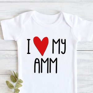 Puede incluir: Un body blanco para bebé con texto negro que dice "I love my AMM" con un corazón rojo en lugar de la "O".