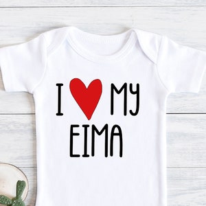 Puede incluir: Un body blanco para bebé con un corazón rojo y el texto "I love my EIMA" impreso en la parte delantera.