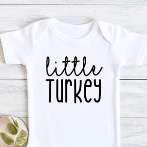Könnte beinhalten: Weißer Baby-Strampler mit schwarzem Text, der "little turkey" lautet.