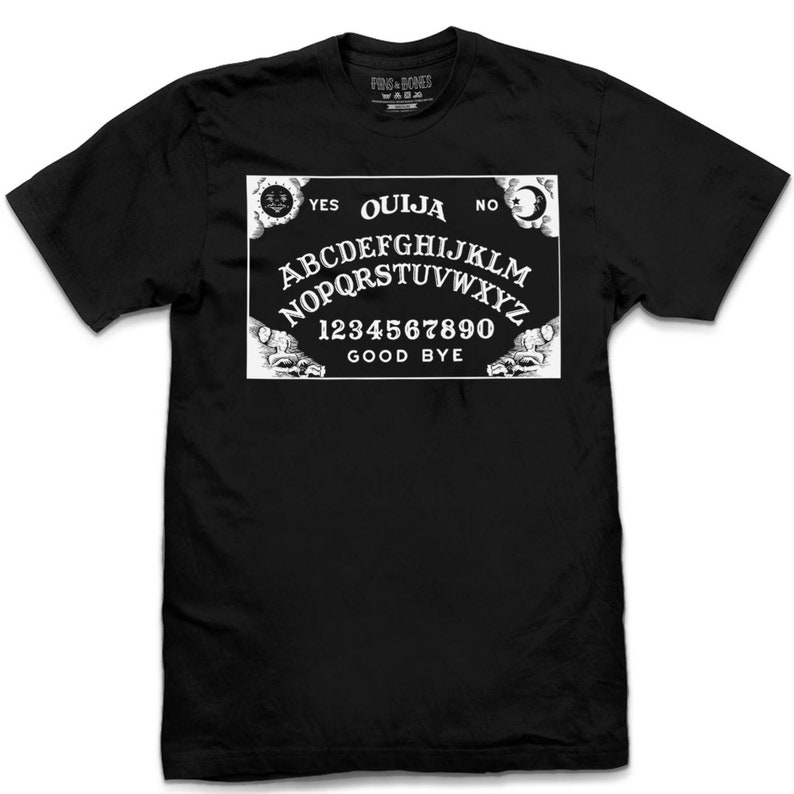 Puede incluir: Camiseta negra con un gr&aacute;fico blanco de una tabla Ouija con las palabras "Ouija", "S&iacute;", "No", "Adi&oacute;s" y las letras del alfabeto y los n&uacute;meros del 1 al 9 y el 0.
