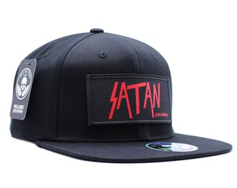 Puede incluir: Gorra de béisbol negra y roja con un parche negro que dice "SATAN" en letras rojas. El parche tiene las palabras "pinks & bones" en letras blancas pequeñas debajo de la palabra "SATAN".