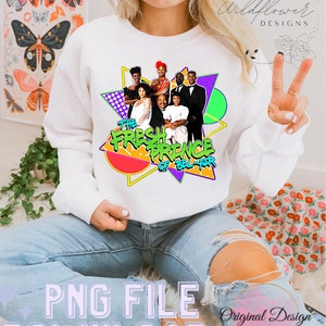 May include: A white sweatshirt with a graphic print of the characters from the television show "The Fresh Prince of Bel-Air". The graphic features the characters in a colorful geometric design with the show's title.