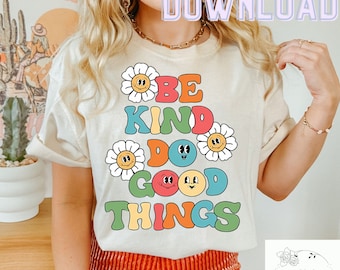 Pode incluir: Uma camiseta branca com um gráfico colorido que diz "Be Kind Do Good Things". O gráfico apresenta margaridas e rostos sorridentes.
