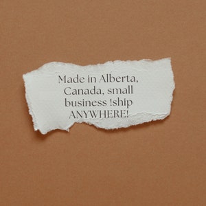 May include: A white piece of paper with torn edges on a brown background. The paper has the text "Made in Alberta, Canada, small business! ship ANYWHERE!" written on it.