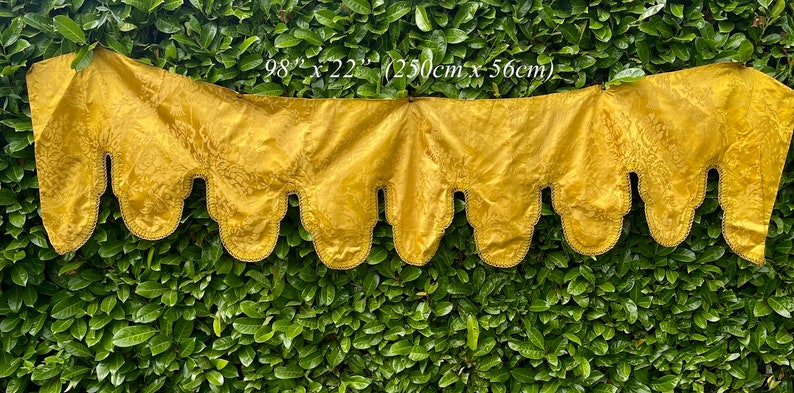 May include: A gold fabric valance with a scalloped edge and a repeating pattern. The valance measures 98 inches by 22 inches (250 cm x 56 cm).