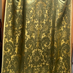 May include: A pair of gold and green damask curtains with a floral pattern. The curtains are made of a heavy fabric and have a luxurious feel.