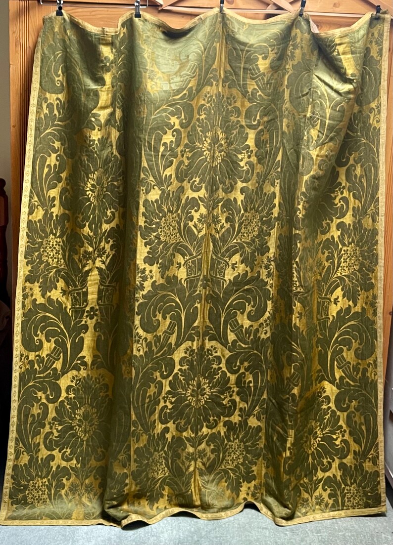 May include: A pair of gold and green damask curtains with a floral pattern. The curtains are made of a heavy fabric and have a luxurious feel.