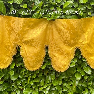 May include: A gold-coloured fabric valance with a scalloped edge and a floral pattern. The valance measures 40 inches by 18 inches (102 cm x 45 cm).