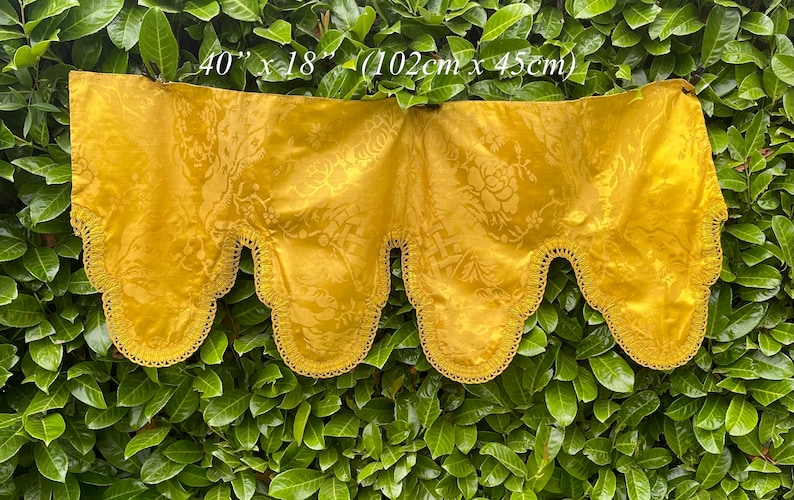 May include: A gold-coloured fabric valance with a scalloped edge and a floral pattern. The valance measures 40 inches by 18 inches (102 cm x 45 cm).