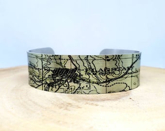 May include: A silver metal cuff bracelet with a vintage map of Flagstaff, Arizona printed on it.