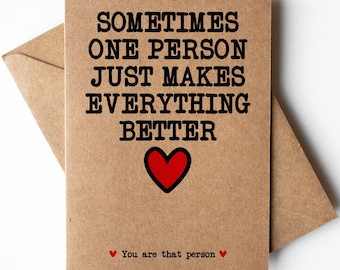 May include: A brown card with the text "Sometimes one person just makes everything better" in black lettering. A red heart is below the text. The text "You are that person" is below the heart in smaller black lettering.