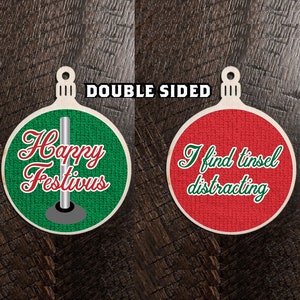 Könnte beinhalten: Doppelseitiger Weihnachtsbaumschmuck mit grünem Hintergrund und dem Text "Happy Festivus" und rotem Hintergrund mit dem Text "I find tinsel distracting".
