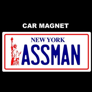 Könnte beinhalten: Ein weißer Automagnet mit einem rot-weiß-blauen Design. Der Magnet zeigt eine Silhouette der Freiheitsstatue und den Text "NEW YORK ASSMAN".