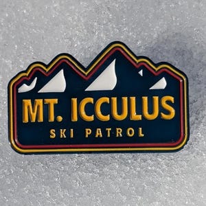 Könnte beinhalten: Eine blaue und gelbe Emaille-Anstecknadel mit einem Bergketten-Design und dem Text "MT. ICCULUS SKI PATROL".