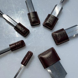 May include: Set of six wood chisels with leather sheaths. The sheaths are numbered 1, 1 1/2, 2, 3/4, 1 1/4, and 1 1/8. The chisels are made of vanadium steel.