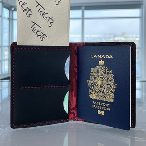 Cartera para pasaporte de cuero negro Heritage Can/USA con forro de filigrana roja