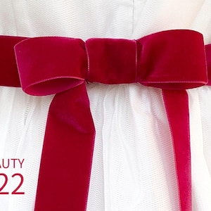 May include: A bright magenta velvet ribbon tied in a bow around a white tulle garment. The ribbon features a smooth, soft texture and is centered horizontally. The text BEAUTY 422 is printed in magenta in the lower left corner of the image.