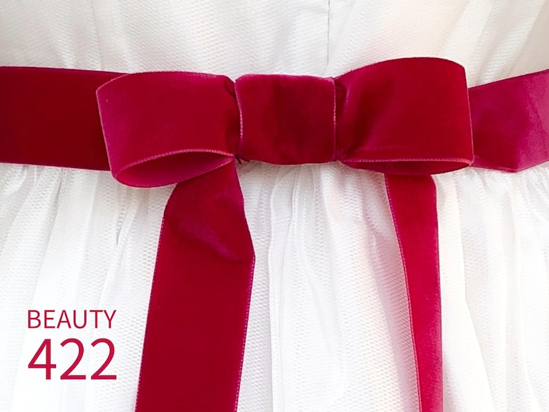 May include: A bright magenta velvet ribbon tied in a bow around a white tulle garment. The ribbon features a smooth, soft texture and is centered horizontally. The text BEAUTY 422 is printed in magenta in the lower left corner of the image.