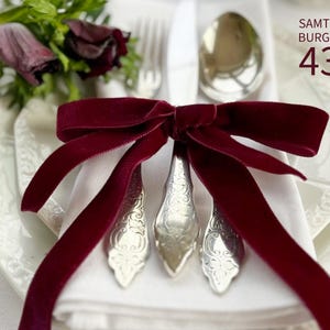 May include: A deep burgundy velvet ribbon tied in a bow around a set of silver-toned metal cutlery, including a fork, knife, and spoon, resting on a white napkin. The text SAMTBAND BURGUNDY 434 is printed in the upper right corner of the image.