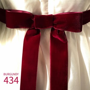 May include: A deep burgundy velvet ribbon tied into a bow, positioned horizontally across a white textured fabric. The text BURGUNDY 434 is printed in the lower left corner of the image in a matching dark red color.