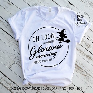 May include: White t-shirt with a black graphic design. The design features the text "OH LOOK! ANOTHER Glorious morning MAKES ME SICK!" inside a circle, with a witch on a broom. The words "POP fizz Clink!" are also visible.