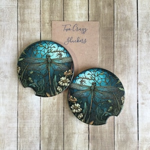 May include: Two round blue and green coasters with a dragonfly design and the text "Two Crazy Shuckers".