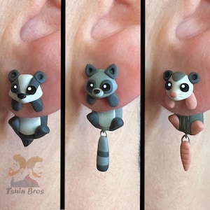 Pode incluir: Brincos artesanais de argila polimérica com desenhos de animais adoráveis. Os brincos apresentam um texugo, um guaxinim com cauda listrada e um gambá com uma cenoura. Cada brinco é uma escultura em miniatura única.