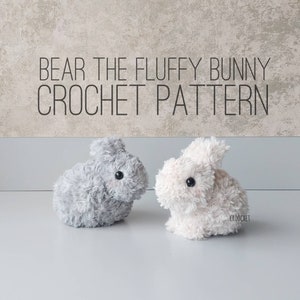 Könnte beinhalten: Zwei flauschige Häkelhasen-Spielzeuge, einer grau und einer weiß, mit schwarzen Knopfaugen. Der Text "BEAR THE FLUFFY BUNNY CROCHET PATTERN" wird über den Hasen angezeigt. Die Hasen sitzen auf einer weißen Oberfläche.