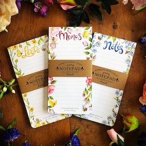 Peut inclure: Trois blocs-notes floraux avec 50 pages lignées. Chaque bloc-notes a un motif floral différent et un titre : "Listes", "Mémos" et "Notes".