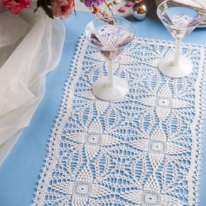 Puede incluir: Un camino de mesa rectangular de ganchillo blanco con un motivo floral repetitivo, costuras caladas intrincadas y un borde festoneado. El diseño incluye una etiqueta PDF file pattern en la esquina superior izquierda, mostrando una textura de encaje detallada.