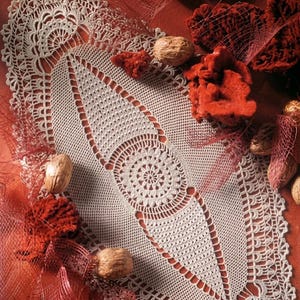 May include: An oval-shaped off-white crochet doily featuring an intricate central circular motif surrounded by geometric lace patterns and a scalloped border. The text PDF File PATTERN is visible in the bottom left corner of the image.