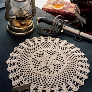 May include: A round, cream-colored crocheted doily featuring an intricate, repeating geometric star pattern in the center, surrounded by an openwork lace border. The text "PDF File PATTERN" is printed in white in the bottom right corner.