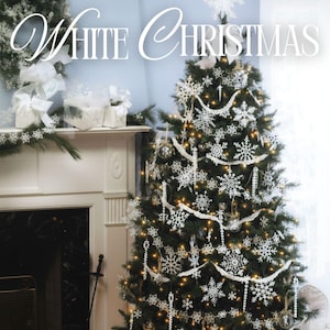 以下が含まれることがあります： 白い雪の結晶のオーナメント、ガーランド、ライトで飾られたクリスマスツリー。上部に「White Christmas」、下部に「54 CROCHETED PROJECTS」と書かれています。ツリーの下にはプレゼントがあります。