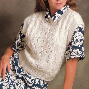May include: A woman wearing a cream-coloured knitted vest with a leaf pattern over a blue and white patterned shirt. The image includes the text "KNITTING PDF PATTERN" in a circular frame.