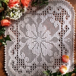 Puede incluir: Un tapete rectangular de ganchillo blanco con un motivo floral central, un patrón de rejilla intrincado y un borde festoneado. El texto PDF File Pattern es visible en la esquina superior izquierda, impreso en una fuente sans-serif simple.