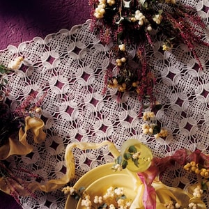 May include: A white crocheted lace tablecloth featuring a repeating geometric pattern, displayed with yellow plates, white berry sprigs, and ribbons. The text PDF File Pattern is visible in the upper left corner of the image.
