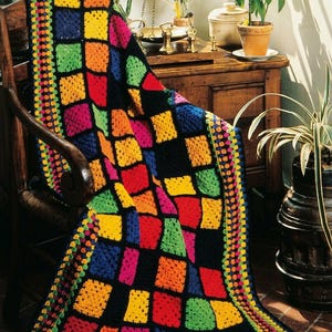 May include: A handmade crochet blanket featuring a vibrant patchwork of square blocks in bright yellow, orange, red, green, blue, and pink, all separated by a black yarn grid. The edges are finished with a multi-colored border of small dots.