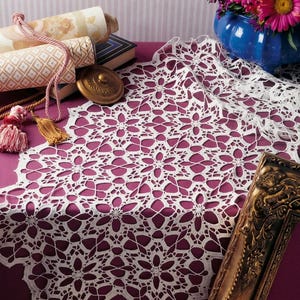 May include: A white crocheted table runner featuring an intricate, repeating floral lace pattern with openwork details. The delicate textile is crafted with fine thread, showcasing a symmetrical design that creates a decorative, scalloped edge.