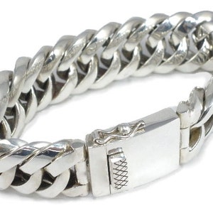 May include: A silver curb chain bracelet with a clasp fastening.